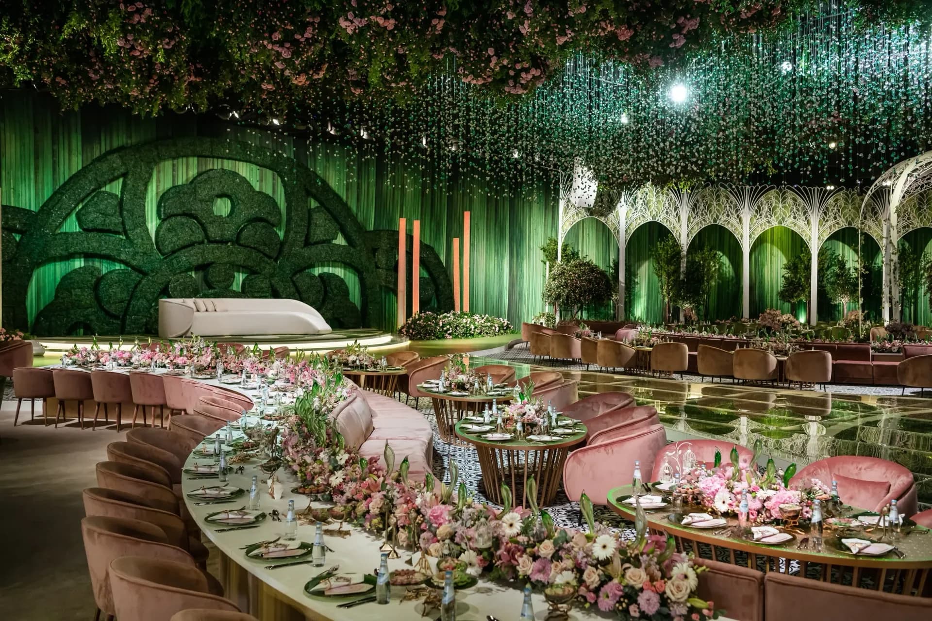 Lush floral wedding setting with chandeliers and a mirrored aisle