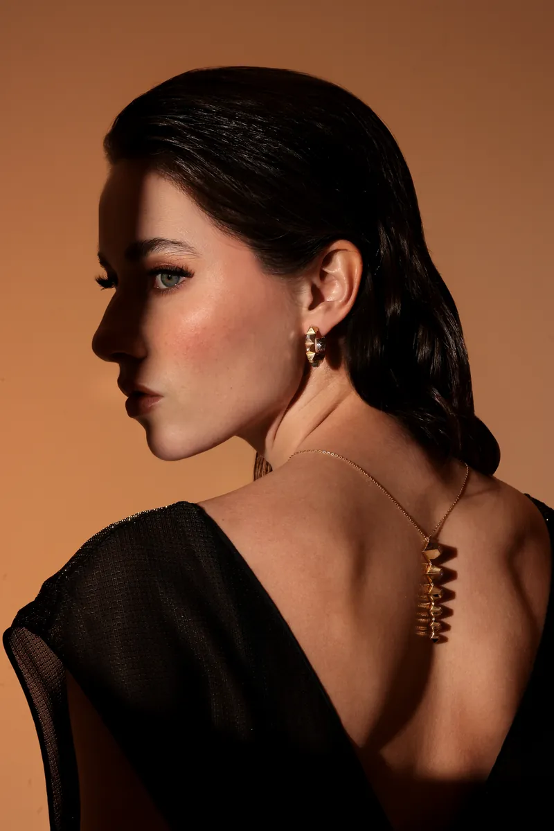 Dina J Jewelry campaign: a long gold pendant necklace worn down an open back