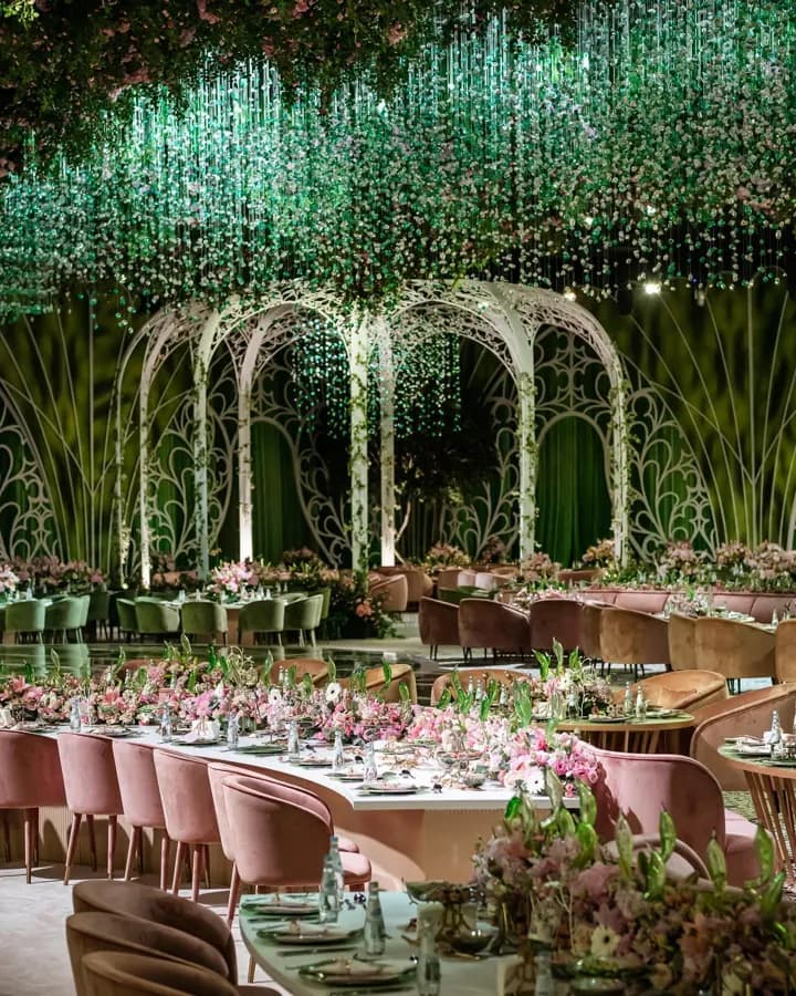 Moements wedding reception: a canopy of green crystals and flowers over pink velvet tables