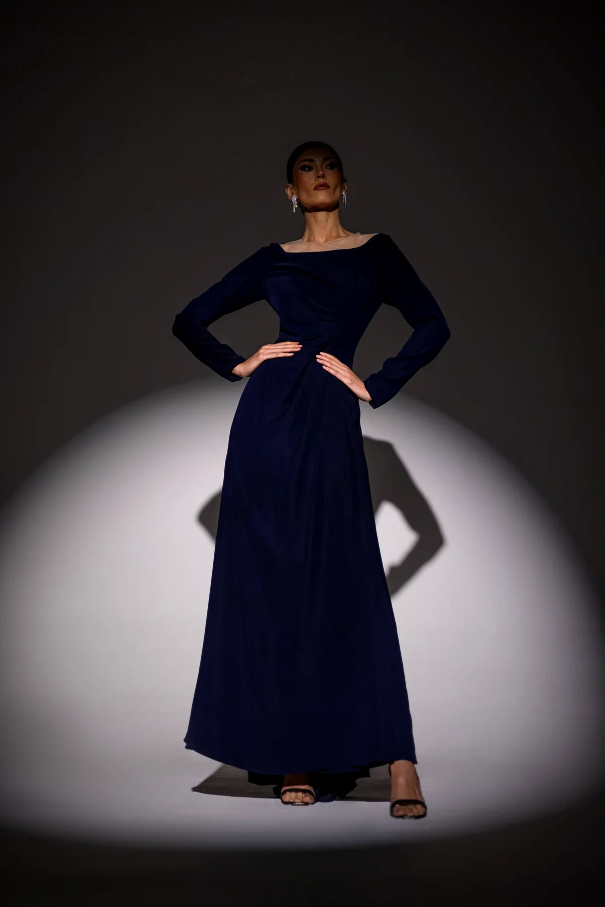 Li Luce campaign: a model in a navy gown under a spotlight