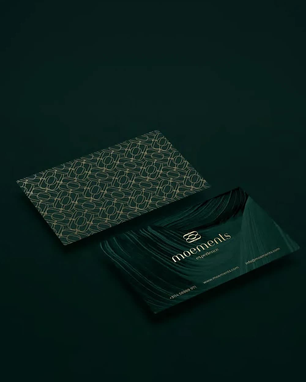 Moements business cards: the gold-foil pattern side and the logo side on deep green
